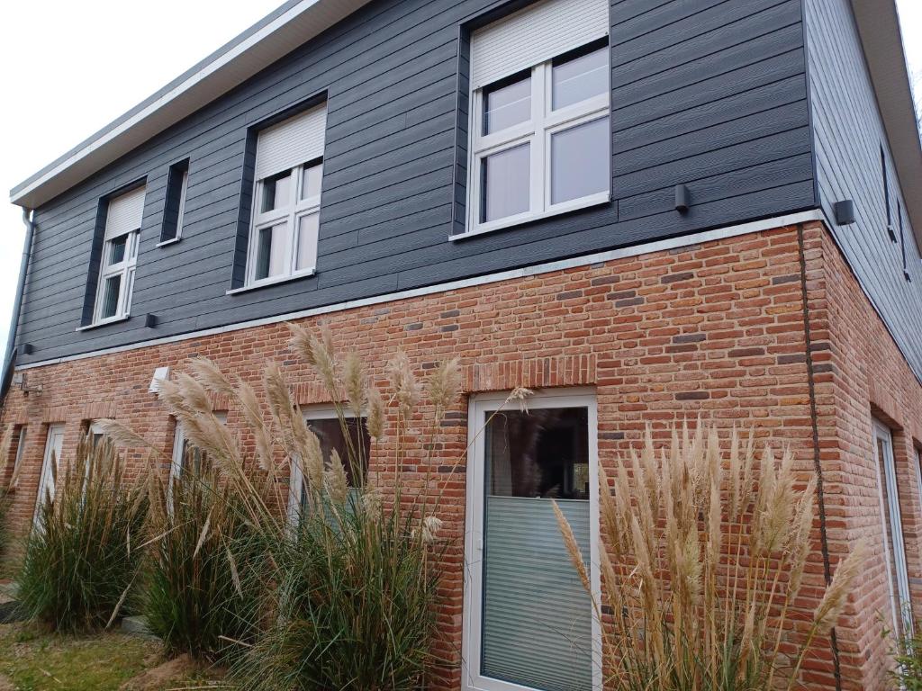 una casa de ladrillo con una puerta y ventanas azules en Sportpension "Seminarhaus an der Eider", en Tönning