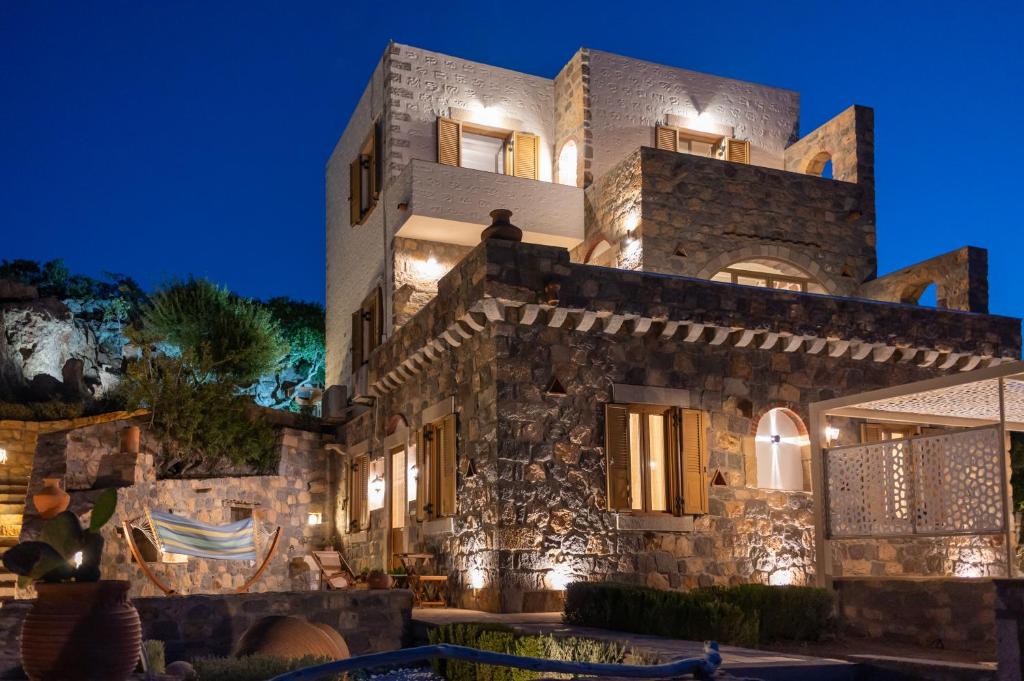 - un grand bâtiment en pierre avec des lumières la nuit dans l'établissement Traditional House Meloi, à Patmos
