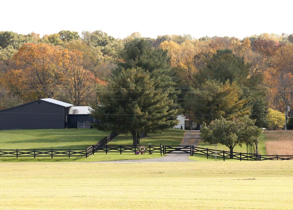 a field with a fence and trees and a barn at Donkeytown at Turner Farms in Heltonville