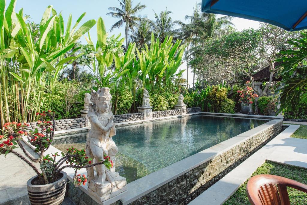a swimming pool with a statue in a garden at Kishi-Kishi ArtVilla for big company in Saba