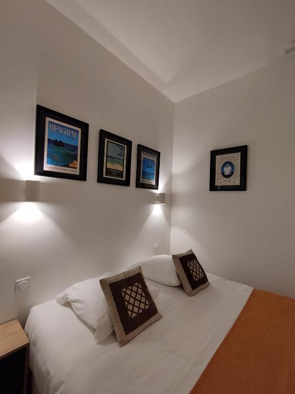 a bedroom with a white bed with three pictures on the wall at The Originals Access, Hotel Le Canter Saumur in Saumur