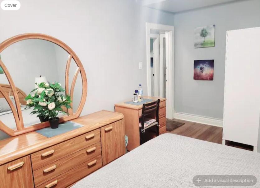 Un dormitorio con un tocador con un jarrón de flores. en Merj's Guest House in Wolesly, en Winnipeg