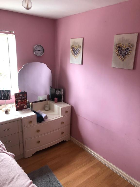 una camera da letto con parete viola, cassettiera e specchio di Room in town centre a Saint Helens