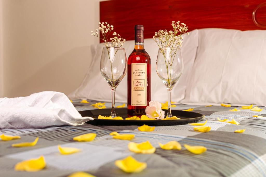 una botella de vino y dos copas de vino en una mesa en YURAQ WASI Hotel/Restobar, en Huánuco