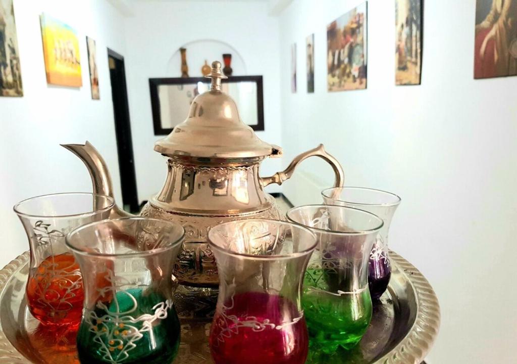 a tea kettle and four glasses on a glass plate at The Marsa story in La Marsa