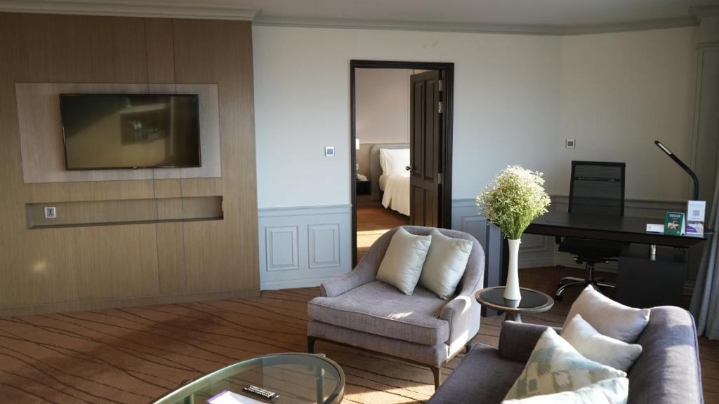 A lounge with a sofa, armchairs, coffee table and a separate desk area.