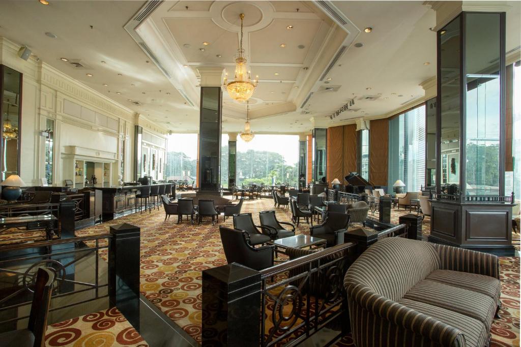 A formal hotel lounge with clustered seating, chandeliers, mirrors, and tall windows.