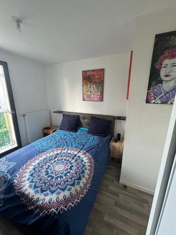 a bedroom with a bed with a blue comforter at Chambre double proche Arena La Defense in Nanterre