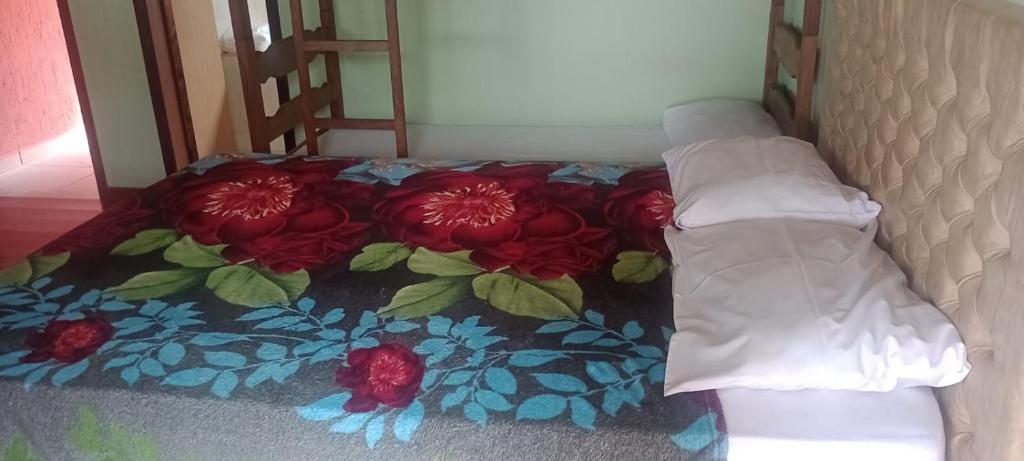 a bed with a blanket with red flowers on it at Pousada Vale dos Sonhos - Suite Master com Hidromassagem in Capitólio