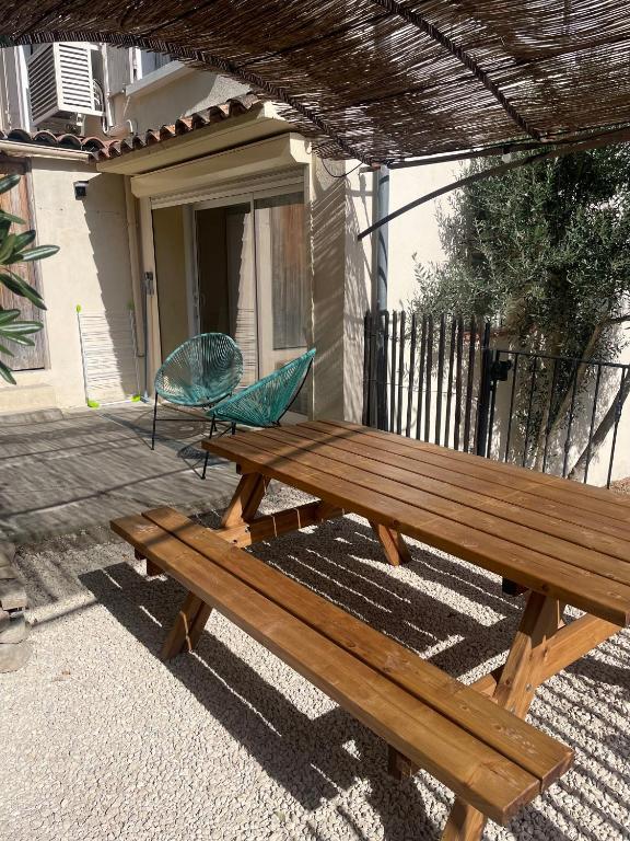 - une table de pique-nique en bois avec un parasol bleu sur une terrasse couverte dans l'établissement Maison de village au pied du Luberon., à Peypin-dʼAigues