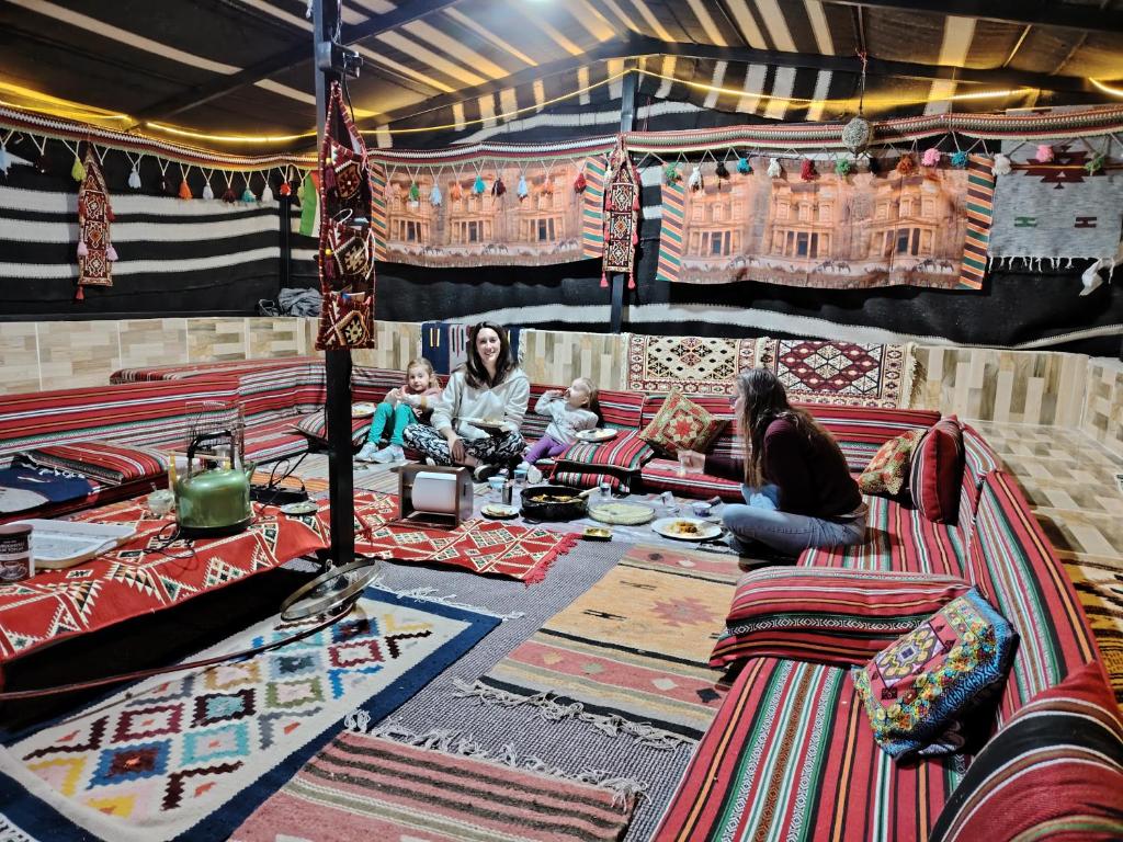 eine Gruppe von Personen, die in einem Zimmer mit Teppichen sitzen in der Unterkunft Petra Magic Guest House in Wadi Musa