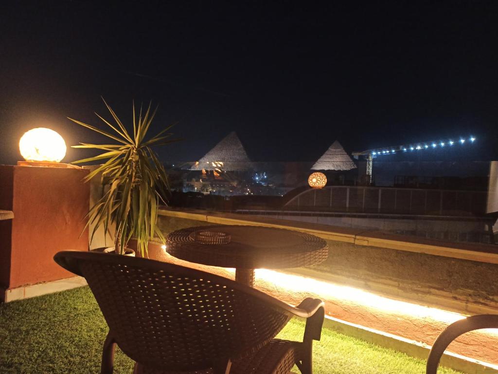 uma mesa e cadeiras numa varanda à noite em Ibis Pyramids&Museum view no Cairo