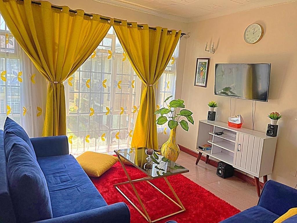 a living room with a blue couch and a tv at Homely apt 3 (three) in Kisumu