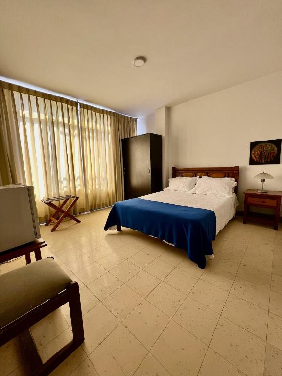 a bedroom with a large bed with a blue blanket at Hotel Armenia Centro in Armenia