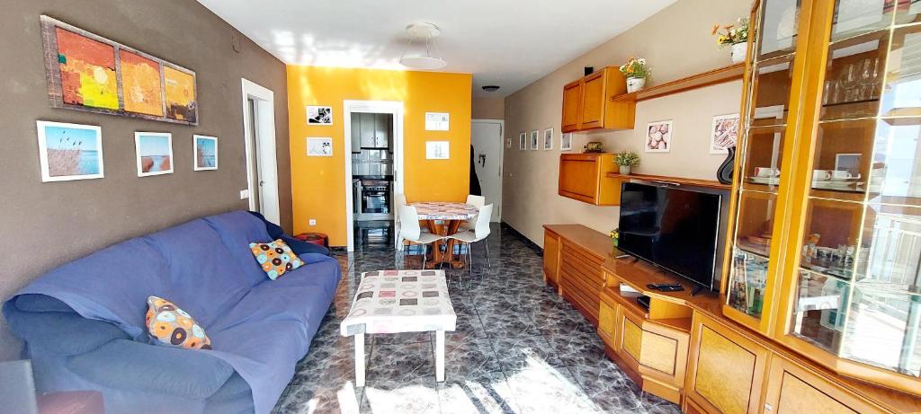 a living room with a blue couch and a tv at Apartamento 1 línea de playa + Parking! Salou in Salou