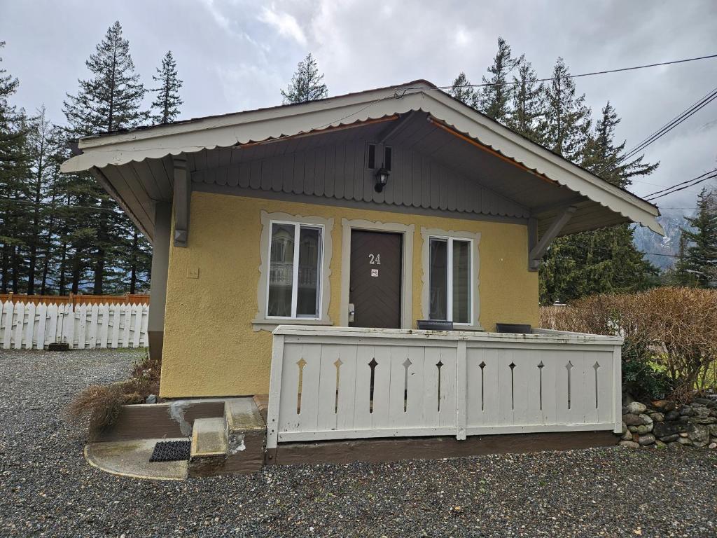 a small yellow house with a white fence at Swiss Chalets Motel in Hope