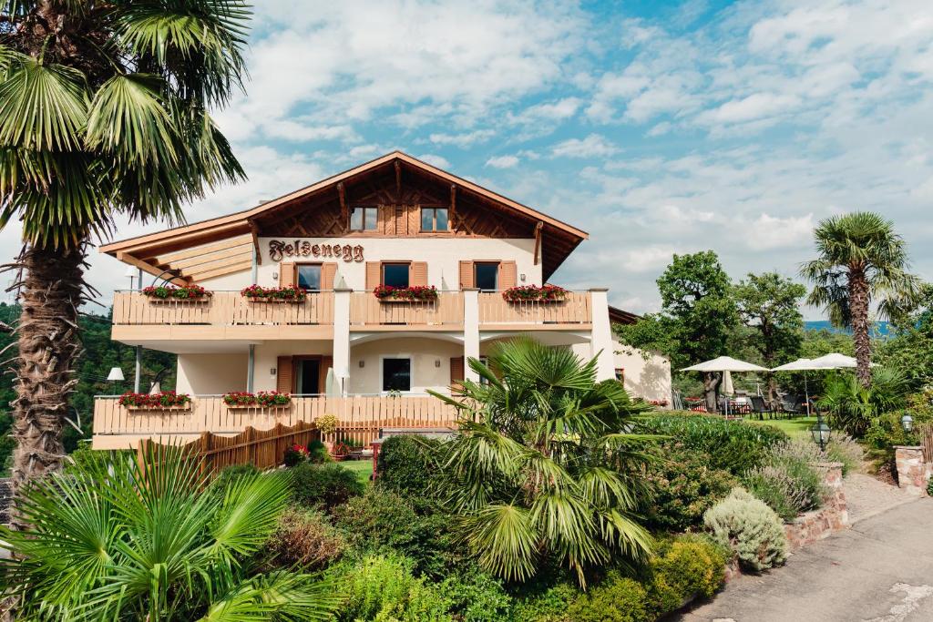 une maison avec un balcon et des palmiers dans l'établissement Felsenegg, à Nalles