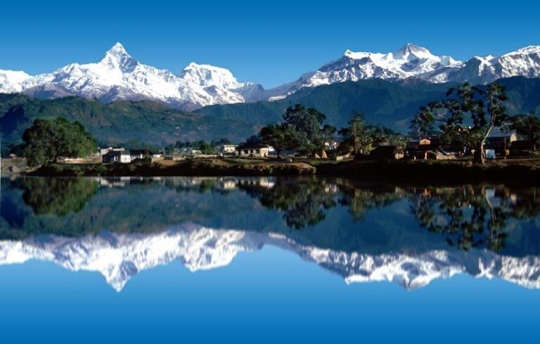 un riflesso delle montagne innevate in un lago di Hello Inn Guest House & Apartment a Pokhara