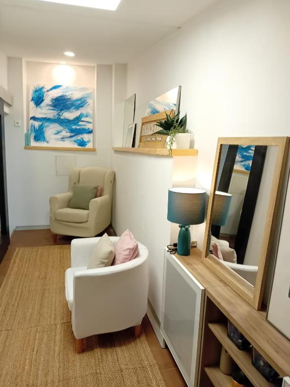 a living room with a white chair and a mirror at Bonavista Montgat in Montgat
