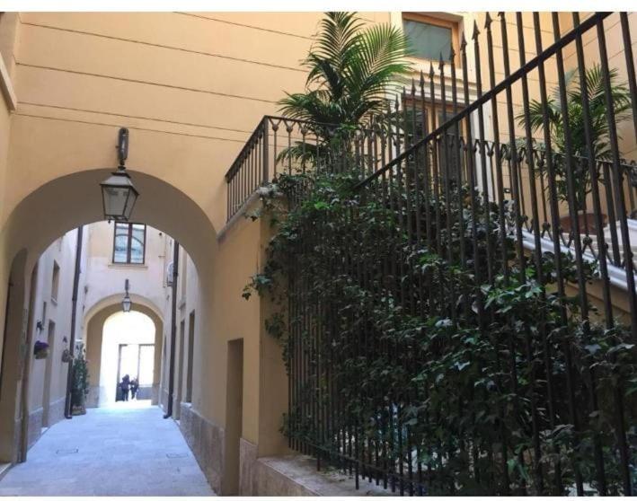 an alley with a fence and palm trees in a building at Martinirooms in Altamura