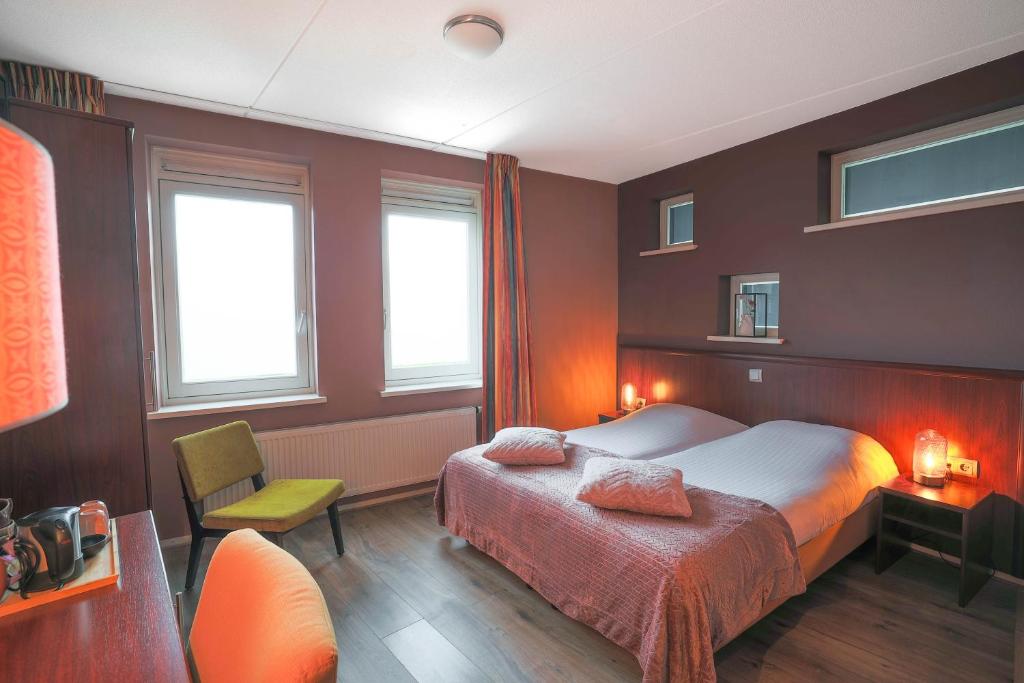 a bedroom with a bed and a chair and windows at Hotel Fase Fier Eten en Drinken in Castricum