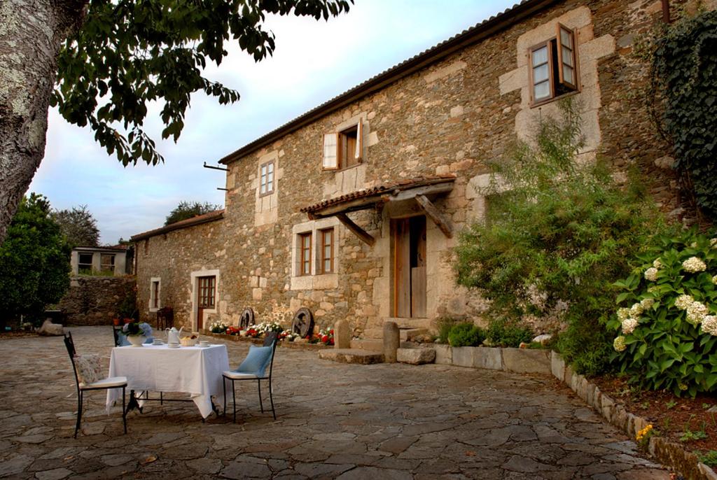 a table and chairs in front of a stone building at Casa de 3 habitaciones in Coirós