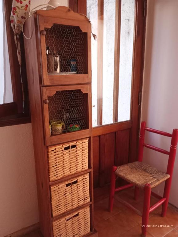 une étagère en bois avec des paniers et une chaise rouge dans l'établissement Departamento"la casa de catita "la pampa general pico, à General Pico