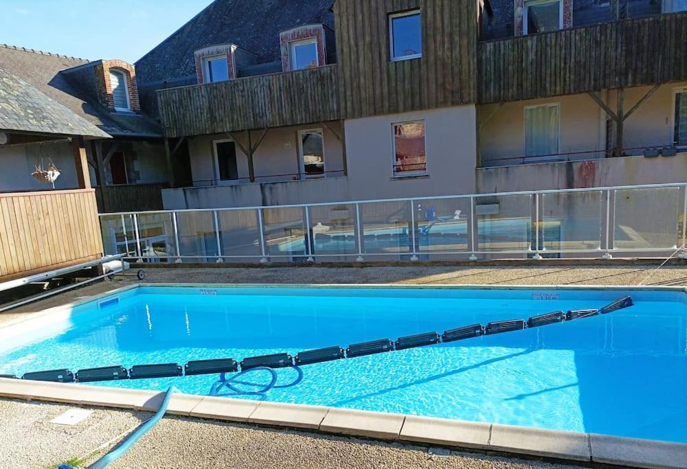 a large blue swimming pool next to a building at Studio cosy Rocherfort en Terre Centre in Rochefort-en-Terre