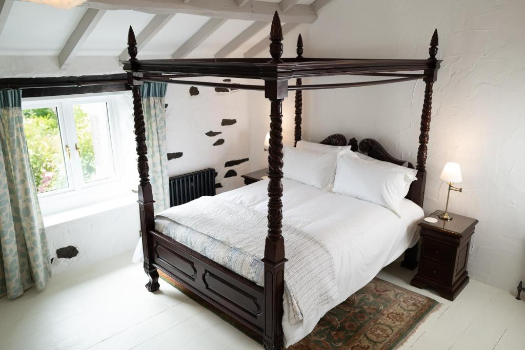 a bedroom with a canopy bed and a window at Bluebell cottage in Ulverston