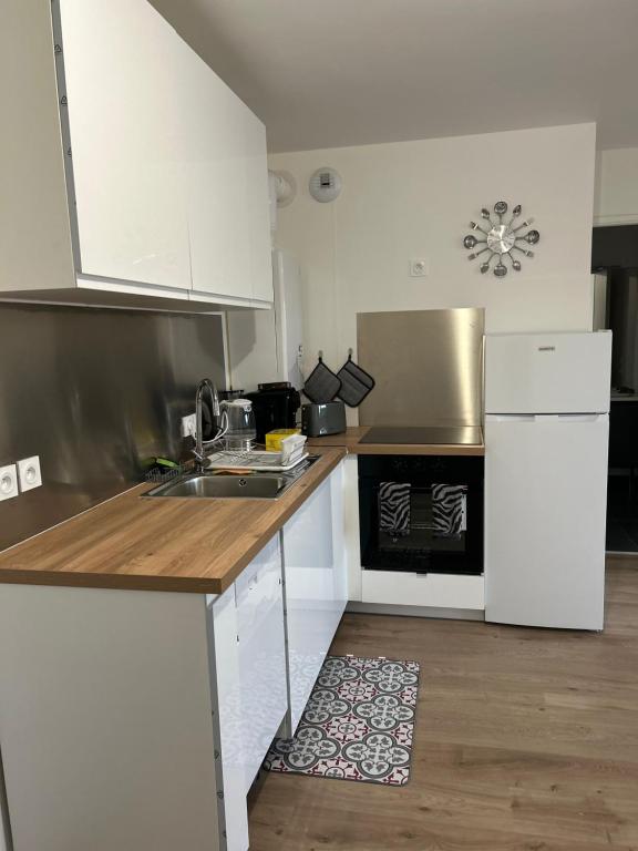 een keuken met witte kasten, een wastafel en een fornuis bij 2 bedrooms proche Paris/CDG/Bourget/Parc des expo in Le Blanc-Mesnil