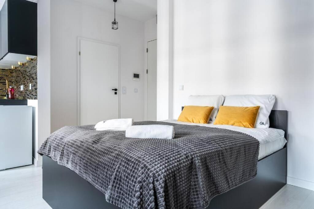 Un dormitorio con una cama con almohadas amarillas. en UrbanNest_Krochmalna en Varsovia