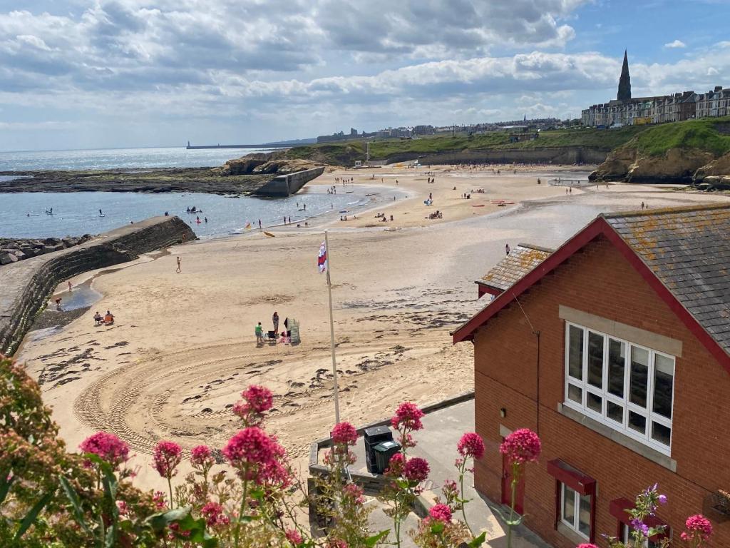 a beach with people in the water and a building at Beach House in Whitley Bay