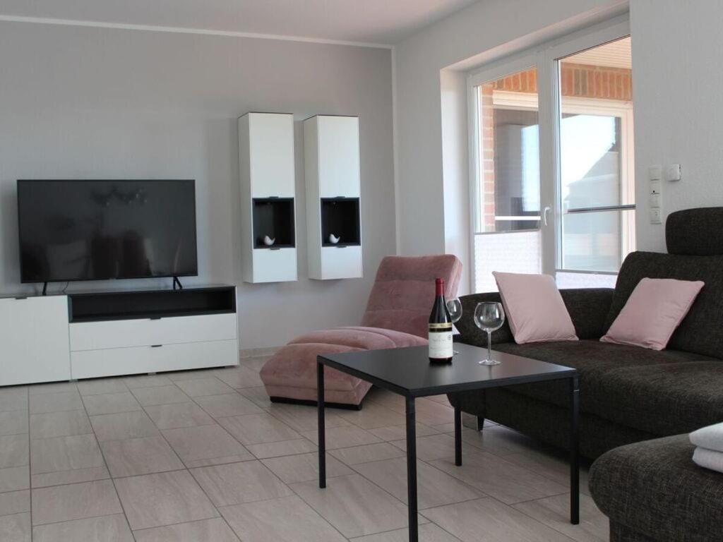 een woonkamer met een tv en een bank en een tafel bij Bungalow Huus Seerose in Krummhörn
