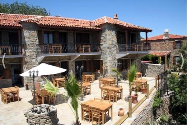 a patio with tables and chairs in front of a building at Degirmen Konukevi in Gokceada Town