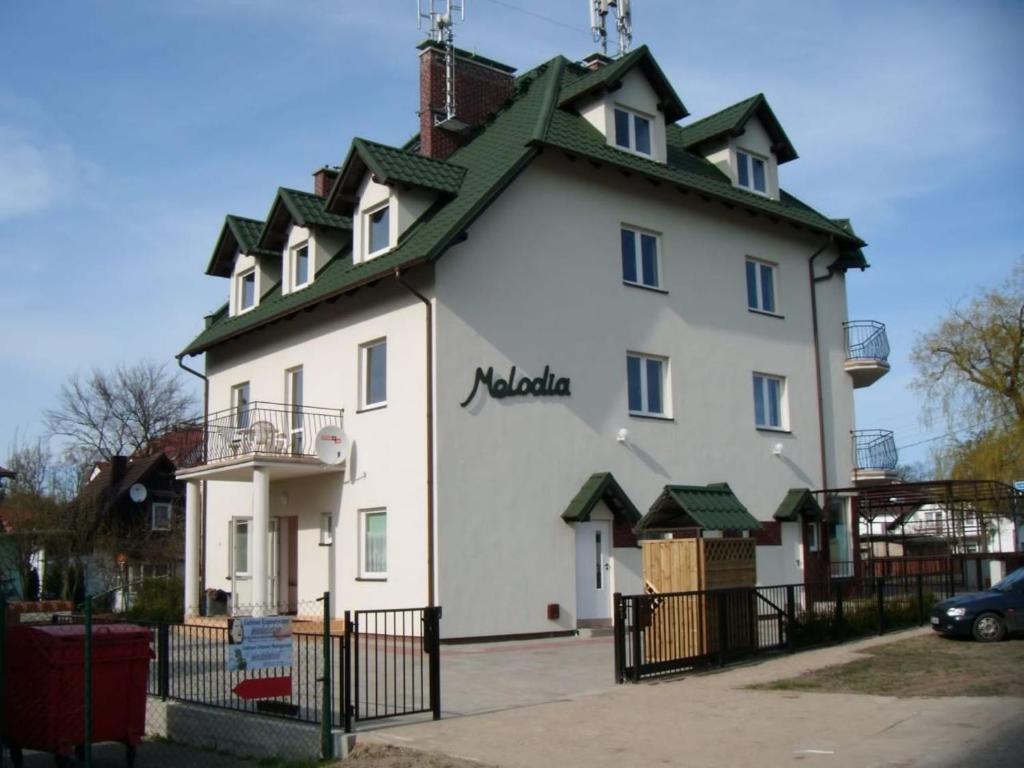 um grande edifício branco com um telhado verde em Pensjonat Melodia em Pobierowo