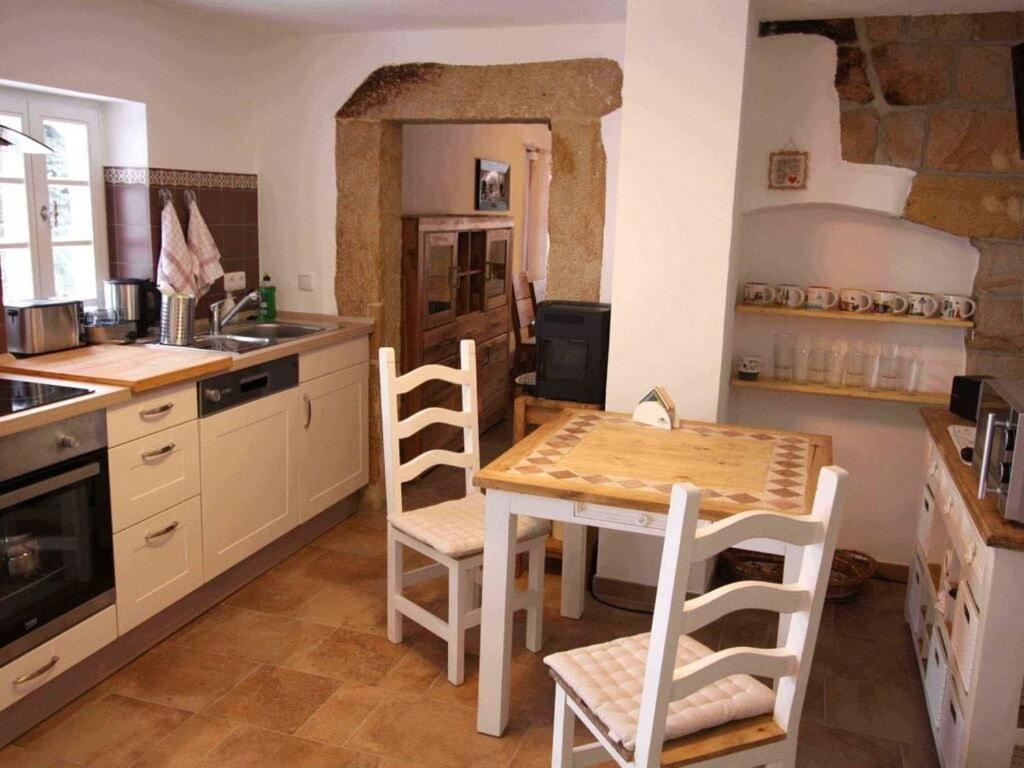 uma cozinha com uma mesa e cadeiras numa cozinha em Holiday home Goßdorf em Hohnstein