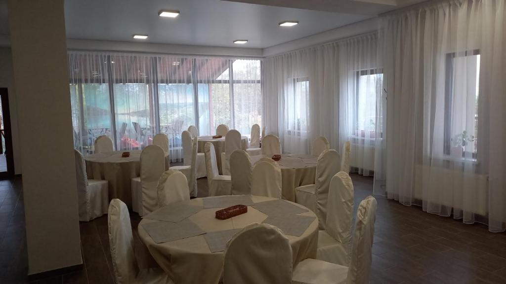a room with white tables and chairs and windows at Pensiunea turistică MUZE in Rezina