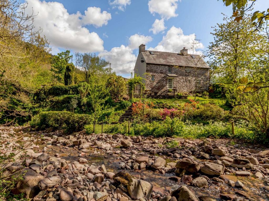 an old stone house on a hill with a rocky stream at 3 Bed in Talybont-on-Usk BN351 in Talybont