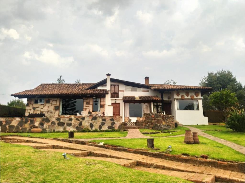 a large stone house with a green yard at Cabañas "Rancho La Mesa" in Pátzcuaro