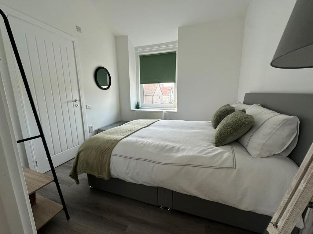 a bedroom with a bed with pillows and a window at Carmen Sylva Studio flat Llandudno sea front in Llandudno