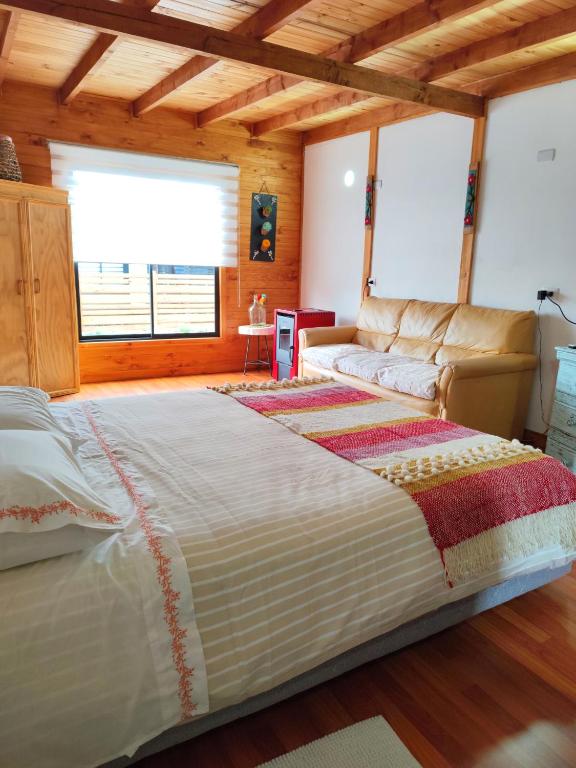 a bedroom with a large bed and a couch at Departamento acogedor in Quellón