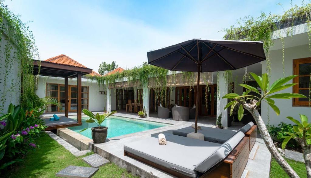 un patio trasero con piscina y sombrilla en Villa in Batu Bolong Canggu, en Canggu