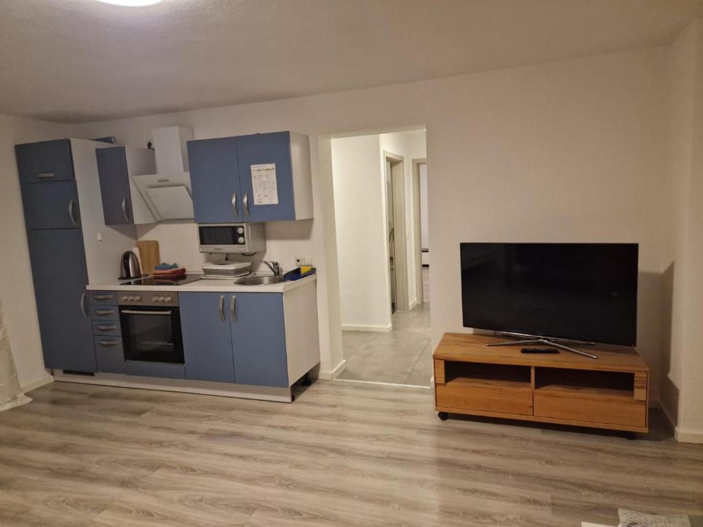 an empty living room with a tv and a kitchen at Ferienwohnung Sumi in Sachsenheim