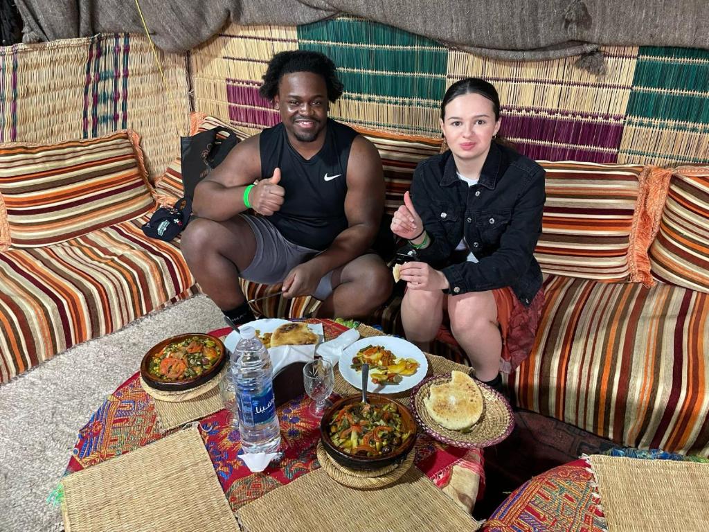 kasbah souss cooking في أغادير: يجلس رجلان على الأريكة مع أطباق من الطعام