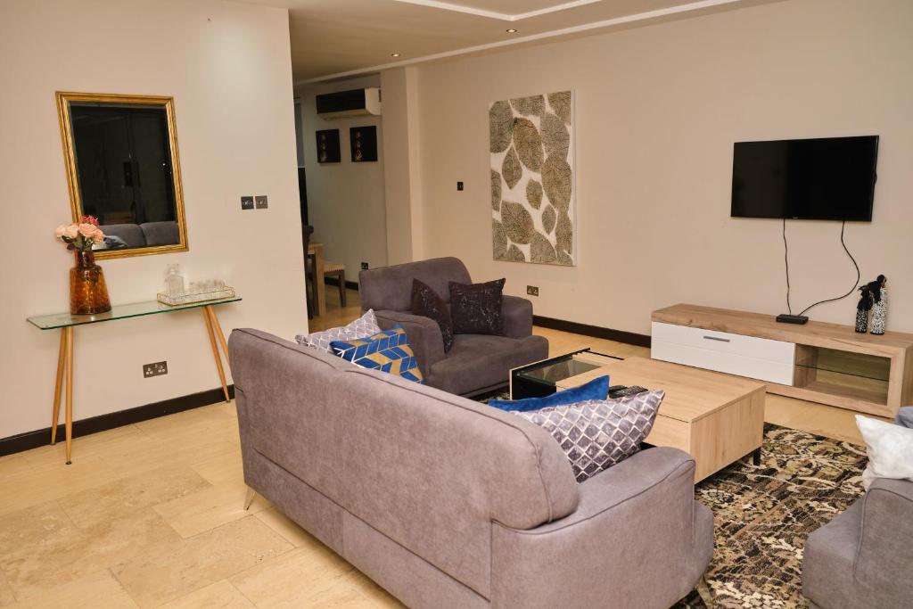uma sala de estar com 2 cadeiras e uma televisão de ecrã plano em Apartment 8 em Acra