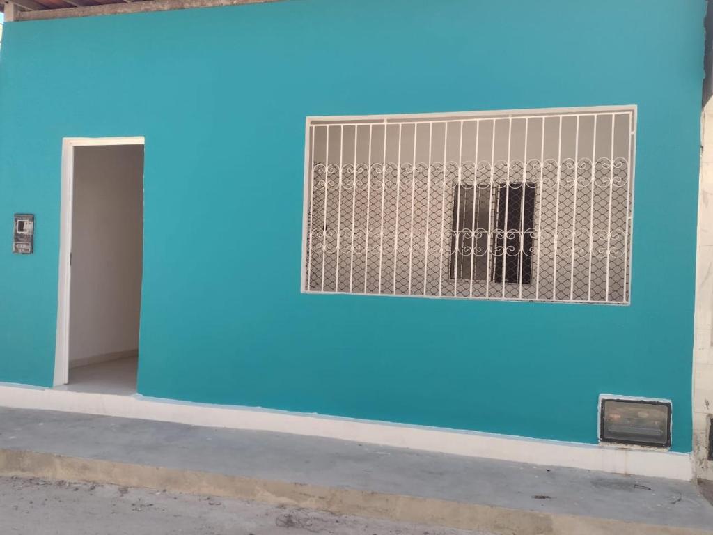 un mur bleu avec une fenêtre et une porte dans l'établissement Casa na Praia de Guaibim- Valença/Bahia, à Guaibim
