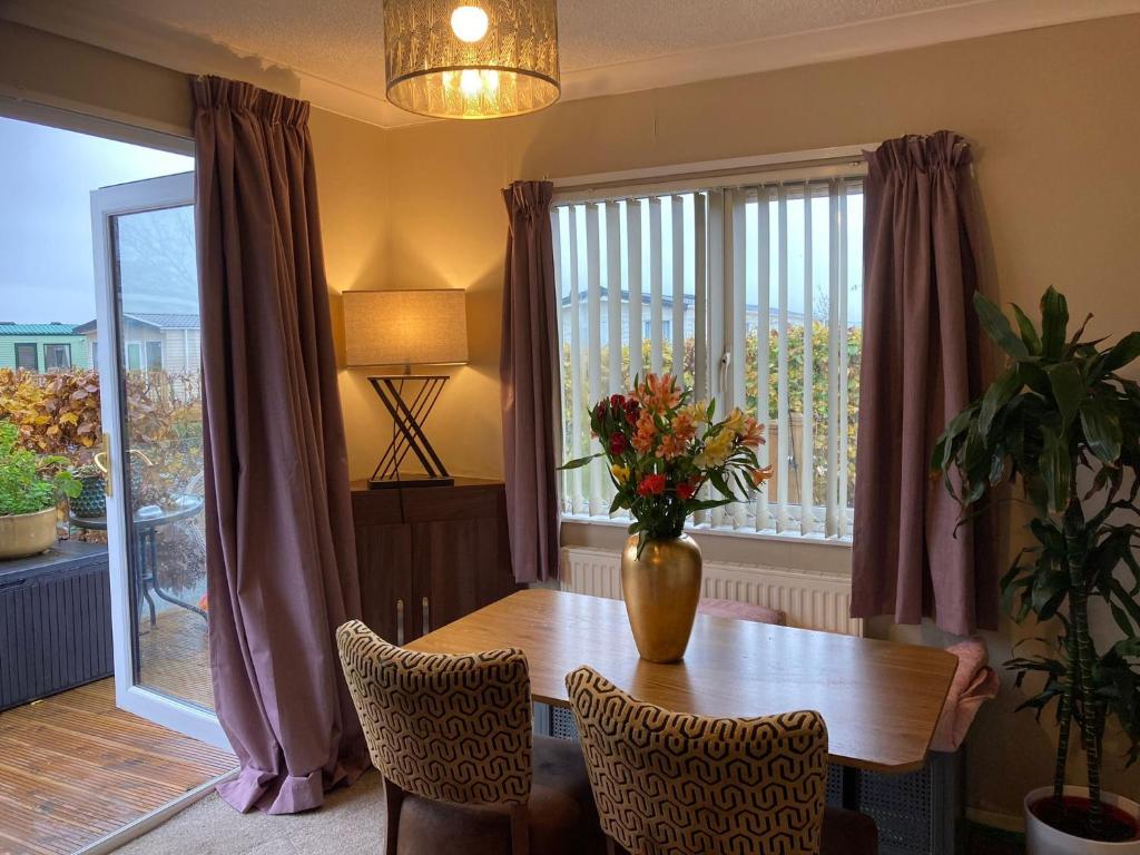 a dining room with a table and a vase with flowers at 2 Bedroomed Lodge with Private Garden in Penrith