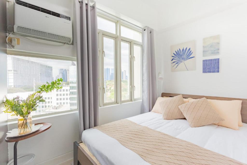 Studio For Rent in Upper Mckinley Hill, Taguig في مانيلا: غرفة نوم بسرير وملاءات بيضاء ونافذة