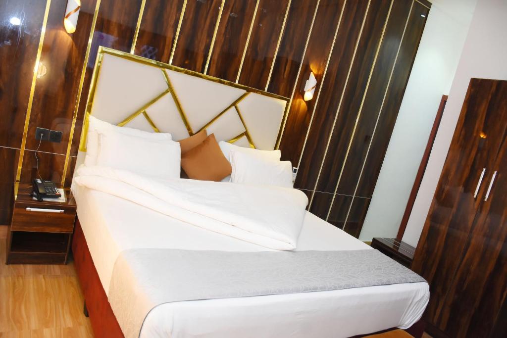 a bedroom with a white bed with a wooden headboard at Grand Seasons Hotel, Nnewichi in Nnewi