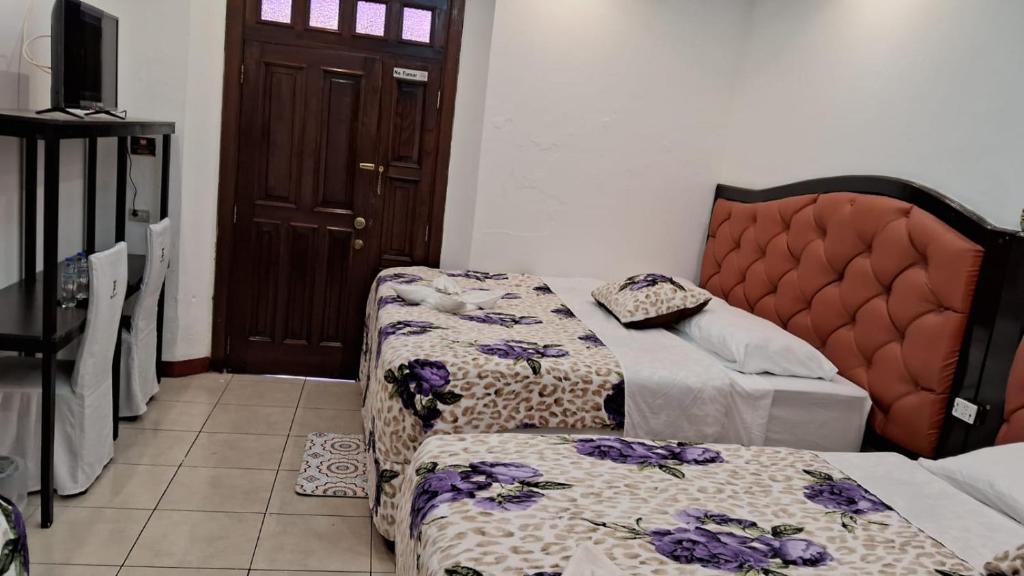 Sala de estar con 2 camas y puerta en Hotel Kamelot Parque Central, en Quetzaltenango
